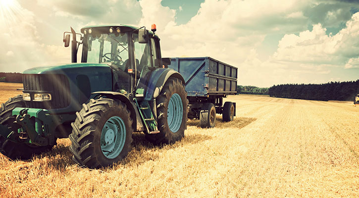 Tractor azul con remolque detenido en un campo