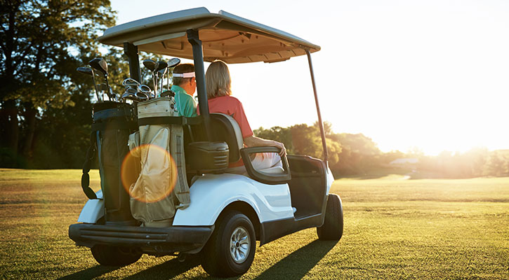 Pareja en un carrito de golf blanco en un campo de golf con tiempo soleado