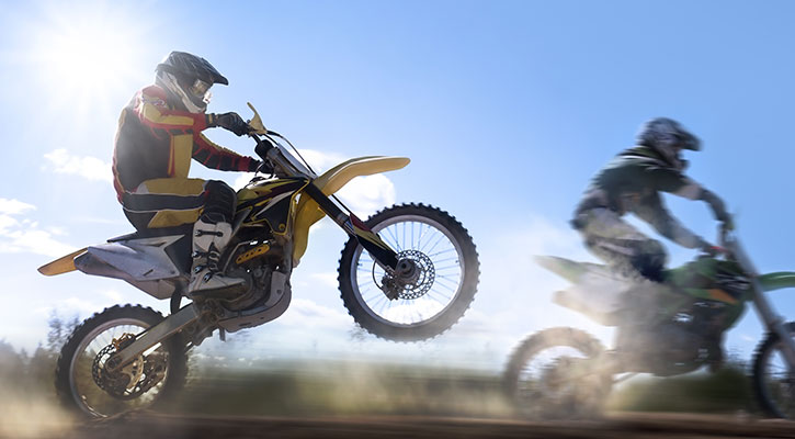 Dos personas circulando en moto por una carretera rural