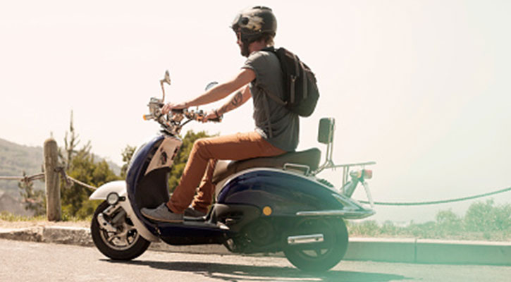 Hombre conduciendo una scooter que se aleja de la cámara